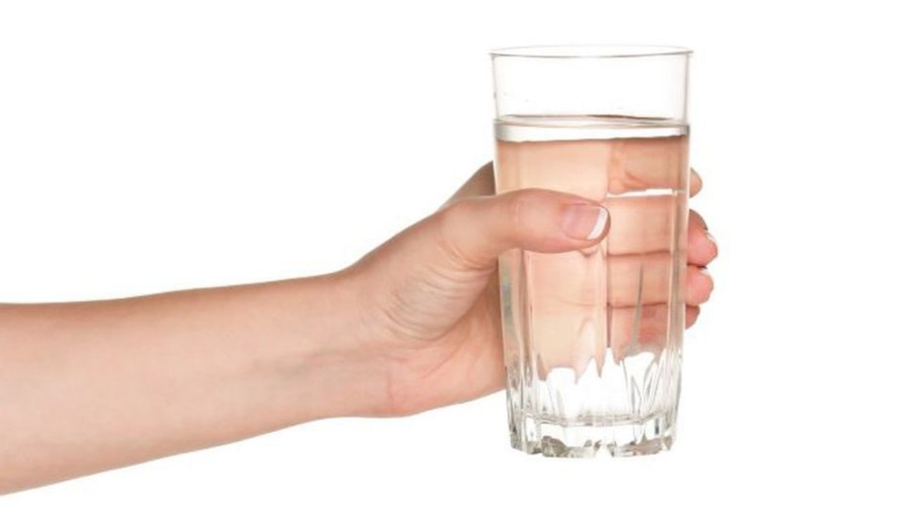 Выпейте стакан воды 1. Рука держит стакан. Стакан воды в руке. Стакан воды в руке на белом фоне. Рука держит стакан в руках.