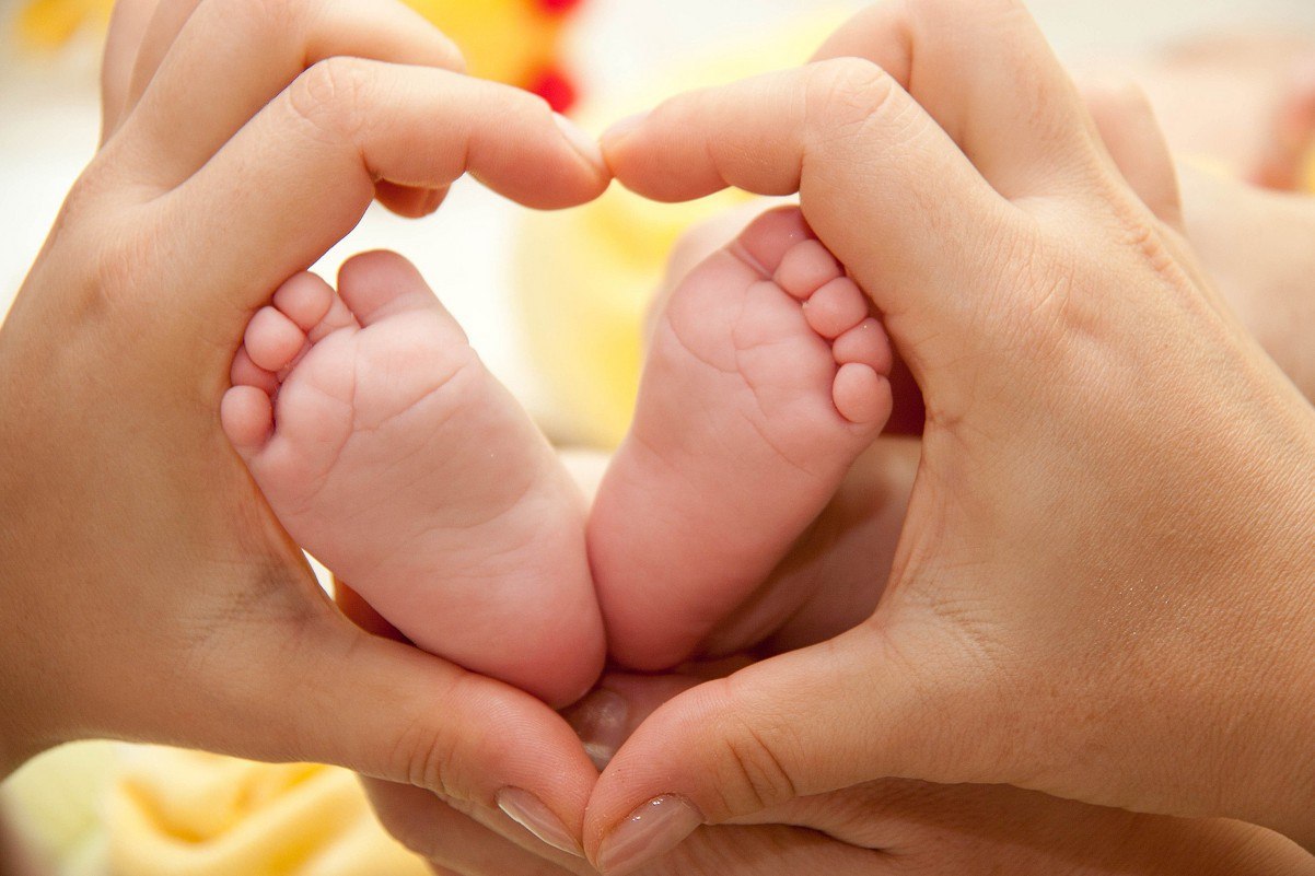 Мама день ноги. Ножки младенца. Ножки ребенка в руках. Пяточки младенца в руках. Малыш и мама.